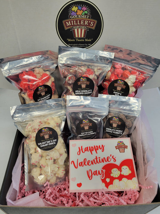 displaying 6 sample size popcorn bags and a Valentines Day card that reads "Happy Valentines Day" in red cursive font. 
Small pink and red hearts along the left edge.  Large red heart in the bottom right corner with two cute popcorn pieces with smiling faces appearing to have popped out of a small pile of popcorn.